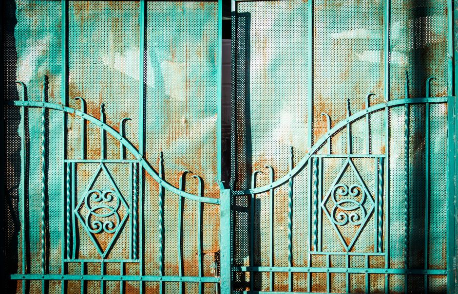 A rustic turquoise metal gate with intricate decorative patterns, perfect for outdoor design themes.
